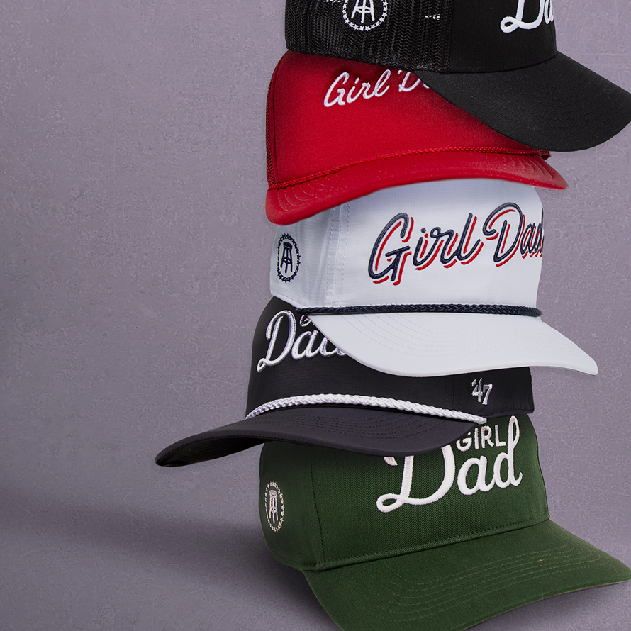 Four baseball caps with 'Girl Dad' text on a gray background